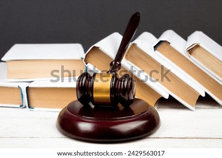 Law concept - Open law book, Judge's gavel, scales, Themis statue on table in a courtroom or law enforcement office. Wooden table, blackboard background