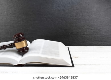 Law concept - Open law book with a wooden judges gavel on table in a courtroom or law enforcement office isolated on white table. Copy space for text