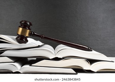 Law concept - Open law book with a wooden judges gavel on table in a courtroom or law enforcement office on blue background. Copy space for text