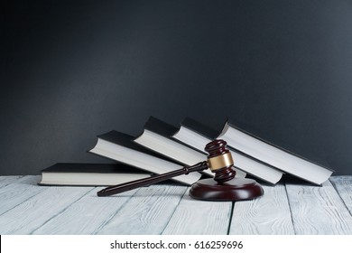 Law concept - Open law book with a wooden judges gavel on table in a courtroom or law enforcement office on blue background. Copy space for text - Shutterstock ID 616259696