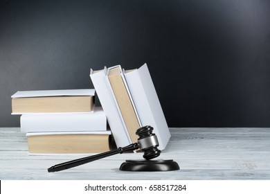 Law concept - Open law book with a wooden judges gavel on table in a courtroom or law enforcement office on blue background. Copy space for text - Shutterstock ID 658517284
