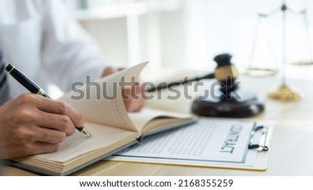 Law consultancy concept A male prosecutor reviewing his sentences of contract on his own notebook before writing them down on the contract paper 