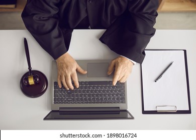 Law Consultation And Legal Advice Online: Professional Senior Judge, Attorney Or Lawyer Sitting At Desk, Working On Laptop, Doing Web Research Or Answering Questions On Website. High Angle, From Above