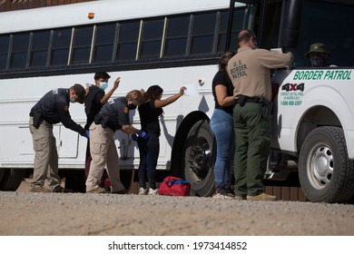 Law enforcement check and search migrants from Columbia after turning themselves over to authorities at the United States and Mexico border May 12, 2021 in Yuma, Arizona.