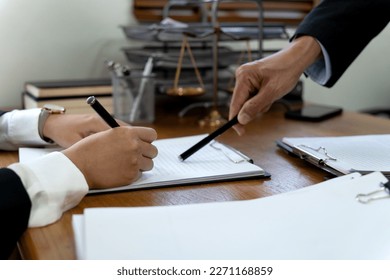 Law firms discussing with pen pointing at documents drafting or amending contracts in law firm office