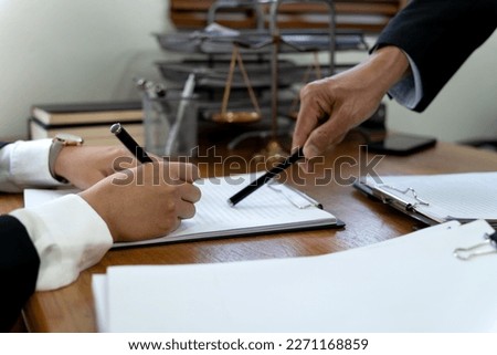 Law firms discussing with pen pointing at documents drafting or amending contracts in law firm office
