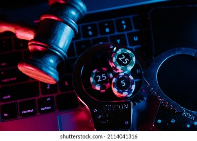 Law and illegal online casino. Wooden gavel, handcuffs and playing chips on keyboard close-up - Shutterstock ID 2114041316