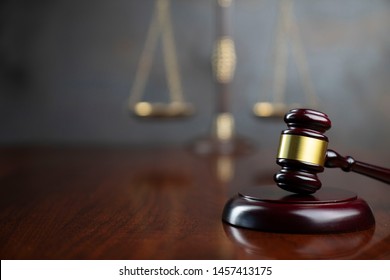 Law and justice concept. Lawyers desk. Judge's gavel, statue of justice, scales, wooden table. Gray bokeh background.