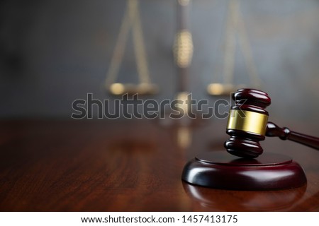 Law and justice concept. Lawyers desk. Judge's gavel, statue of justice, scales, wooden table. Gray bokeh background.