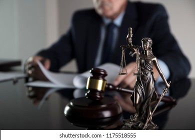 Law and justice concept. Male judge on gray background, statue of justice, gavel, bokeh.