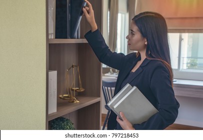 Law Student Trainee Searching For Law Books In The Library At Law Office