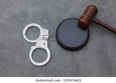 Law theme. Court of law trial in session. Judge gavel handcuffs on grey table in lawyer office or court session. Mallet of judge on concrete stone grey background. Justice human rights concept