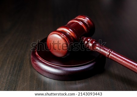 Law theme. Court of law trial in session. Judge gavel on wooden table in lawyer office or court session. Mallet of judge on dark background. Justice human rights concept