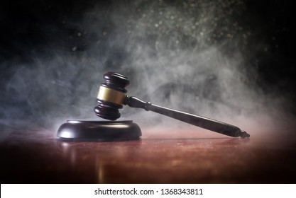 Law theme, mallet of the judge on wooden desk with Lady Justice Statue. Law gavel on dark foggy background with light. Selective focus