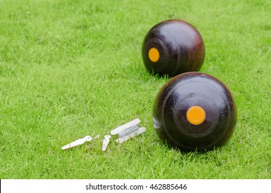 Lawn Bowls. Two wooden bowling balls on freshly cut grass with measuring device. Landscape with copy space.