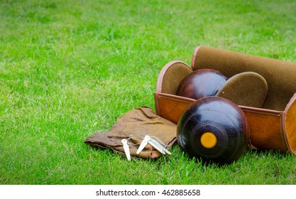 Lawn Bowls. Two wooden bowling balls on freshly cut grass with measuring device, leather bag and cloth. Landscape with copy space.