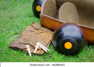 Lawn Bowls. Two wooden bowling balls on freshly cut grass with measuring device, leather bag and cloth. 