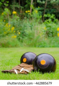 Lawn Bowls. Two wooden bowling balls on freshly cut grass with measuring device and leather cloth. portrait with copy space.
