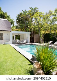 Lawn Chairs And Swimming Pool In Backyard