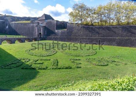 Lawn in front of the citadel in Belfort on which the word Belfort and a cyclist symbol have been mown into the lawn. The citadel can be seen in the background.