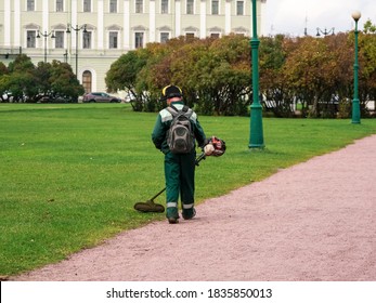 Lawn Mower From The Back At Work. City Service, Maintenance Of The City Lawn In The Park. Saint Petersburg.