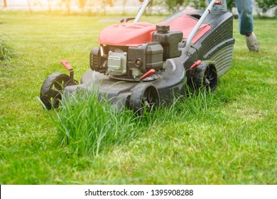 Lawn mower cutting green grass, gardener with lawnmower working, city courtyard of an apartment building - Shutterstock ID 1395908288