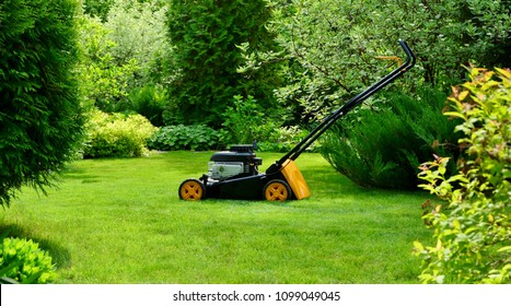 Lawn Mower On The Lawn On A Sunny Summer Day In A Beautiful Garden.