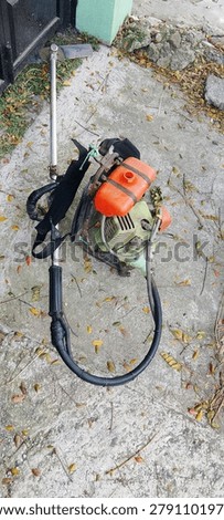 Lawn mower A rather old and rusty piece of heavy equipment, with a striking orange petrol tank