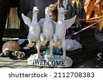 A lawn ornament of three white geese with their wings wrapped around each other representing friendship. The base says WELCOME.