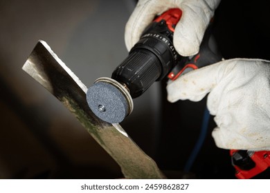 Lawnmower blade being sharpened with drill attachment. - Powered by Shutterstock