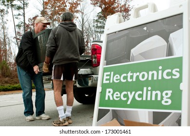  LAWRENCEVILLE, GA - NOVEMBER 23:  Two Men Carry A Discarded TV Past An 