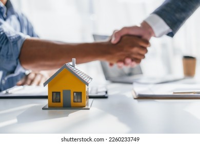 Lawsuits against Real estate agent and realtor general liability insurance businessman professional discussing and consultant with house toy model building shaking hands after sign a contract