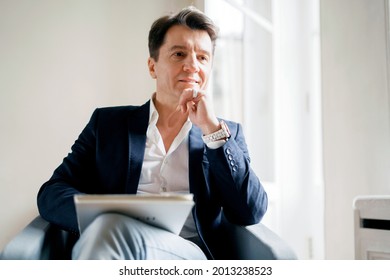 The lawyer is an adult man with gray hair, sitting in a business suit and thinking. The lawyer is a successful stylish man who holds the legislation of the country in his hands.A business person in a 