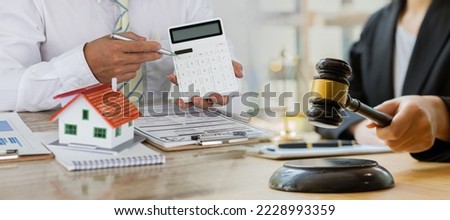 Lawyer or businessman sitting at table with fair scales Hammer and small wooden toy house work with documents Sign a contract agreement Real estate law, auction house concept