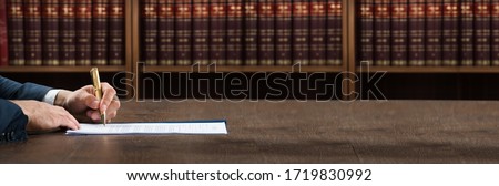 Lawyer Doing Legal Document Scrutiny At Desk With Books At Background 