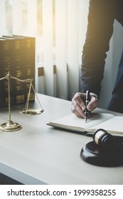 Lawyer Hand Holding Pen And Providing Legal Consult Business Dispute Service At The Office With Justice Scale And Gavel Hammer.