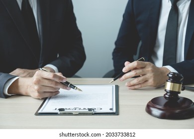 Lawyer Hand Holding Pen And Providing Legal Consult Business Dispute Service To The Man At The Office With Justice Scale And Gavel Hammer.