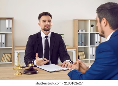 Lawyer having a meeting with a new client. Young male attorney in suit and tie sitting at office desk, sharing legal advice, explaining inheritance process, trying to help. Law consultation concept