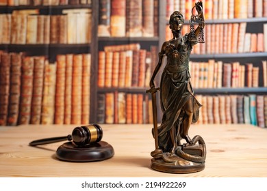 Lawyer Office. Statue Of Justice, Scales And Judge's Gavel Against The Backdrop Of A Wall Of Books Or A Library . Legal Law, Advice And Justice Concept