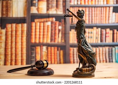 Lawyer Office. Statue Of Justice, Scales And Judge's Gavel Against The Backdrop Of A Wall Of Books Or A Library . Legal Law, Advice And Justice Concept