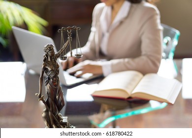 Lawyer office. Statue of Justice with scales and lawyer working on a laptop. Legal law, advice and justice concept.