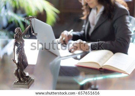 Lawyer office. Statue of Justice with scales and lawyer working on a laptop. Legal law, advice and justice concept.
