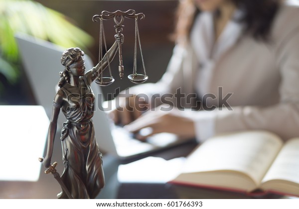Lawyer\
office. Statue of Justice with scales and lawyer working on a\
laptop. Legal law, advice and justice\
concept.