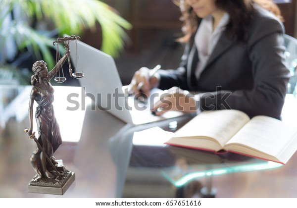 Lawyer\
office. Statue of Justice with scales and lawyer working on a\
laptop. Legal law, advice and justice\
concept.\
