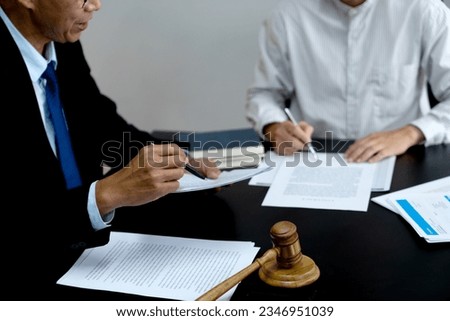 Lawyer pointing to document and discussing legal text in lawsuit or firm drafting paper document with assistant or client
