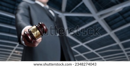 The lawyer pulls up a gavel against the background of the ceiling of the court.