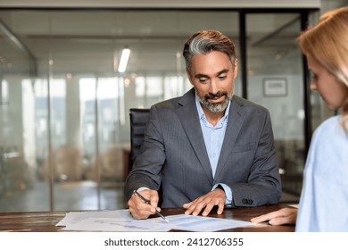 Lawyer or real estate agent make consultation for client. Mature Latin business man and European business woman discussing project on laptop sitting at table in office. Business people work together. - Powered by Shutterstock