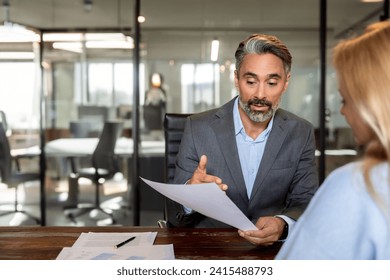 Lawyer or real estate agent make consultation for client. Mature Latin business man and European business woman discussing project on laptop sitting at table in office. Business people work together. - Powered by Shutterstock