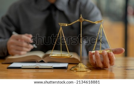 A lawyer is trying his hand under the scales of justice, he is a lawyer who has to uphold the principles of fairness and justice. Lawyer concept and the use of law properly and fairly.