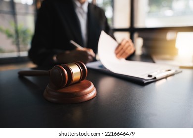 Lawyer Working With Wooden Gavel Of Judge At The Desk, Working In Laptop, With Document Contract, At Law Firm, Lawsuit And Justice Concept.